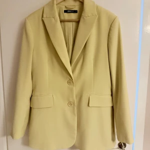 Gul kavaj från ginatricot - Elegant gul kavaj från Ginatricot med klassisk design. Kavajen har långa ärmar och stängs med två knappar framtill. Perfekt för en stilren look. Köpt på gina för 600🤍 använd en gång, säljer även matchade kostymbyxor till🤩