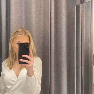 Vit klänning - Säljer en stilren vit omlottklänning från Bik Bok. Klänningen har långa ärmar och en v-ringad design med knytning i midjan. Absolut skrynklig, men strykning ingår vid köp av varan 😌 Nypris 449. Använd 2 tillfällen.