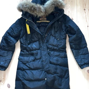 Svart dunjacka från Parajumpers - Säljer en svart dunjacka från Parajumpers med päls på huvan. Jackan har en slim fit passform och är perfekt för kalla vinterdagar. Den har flera praktiska fickor och en dragkedja framtill. Märkesdetaljer finns på ärmen. Behöver sys i ena fickan inget som syns. 