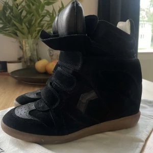  Bekett sneakers från Isabel Marant - Följ mig jättegärna för liknande plagg! Funderar på stt sälja dessa ursnygga svarta sneakers från Isabel Marant med hög sula och kardborreband. Skorna har en kombination av skinn och mocka vilket ger en stilren look. Perfekta för att ge lite extra höjd och stil till din outfit. I toppskick och SÅ trendig🩷🩷🩷 ÄKTA säljer inte under 3000🩷🩷