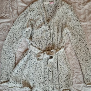 Grå stickad kofta med bälte - Mysig grå stickad kofta med ett bälte i midjan. Koftan har långa ärmar och ett melerat mönster. Perfekt för kyliga dagar.