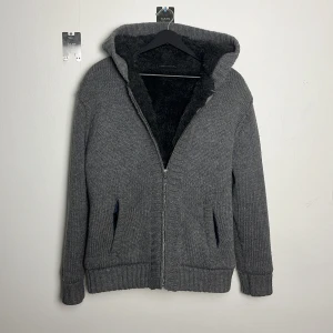 Grå Stickad hoodie med päls - Riiiktigt schysst, varm och lining i ärmarna. Tyvärr lite för liten för mig, jag är 183cm, 83 kg. Det står S i men skulle säga M