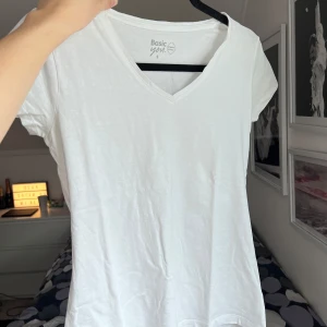 Vit t-shirt från Basic You - Säljer en vit t-shirt från Basic You i ekologisk bomull. Den har en v-ringad hals och korta ärmar, perfekt för en enkel och stilren look. Passar bra till både jeans och kjol. Storlek: S. Axel: 37cm. Längd: 60cm.