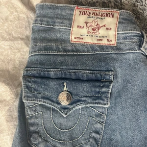 Blå jeans från True Religion - Jag säljer ett par snygga blå jeans från True Religion, modell Joey Low Rise Flare. De har en låg midja och utsvängda ben. Jag säljer de för att de inte kommer till användning. Har endast använts ett fåtal gånger och har inga defekter💘