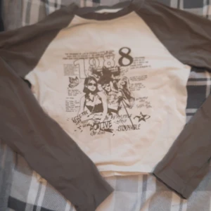 Vit och Moss grön långärmad tröja med tryck - Säljer en vit och Moss grön långärmad tröja med ett retroinspirerat tryck från 1988 på framsidan. Tröjan har raglanärmar och är perfekt för en avslappnad stil. Passar bra till jeans eller shorts för en casual look.