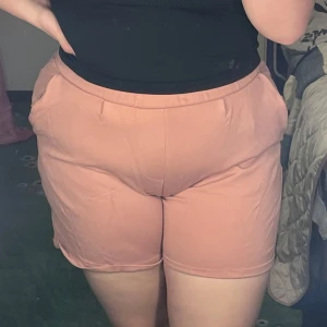 Rosa shorts - Säljer ett par bekväma rosa shorts med elastisk midja och fickor. Perfekta för en avslappnad stil. De har en enkel design som gör dem lätta att matcha med olika toppar. Storlek L!