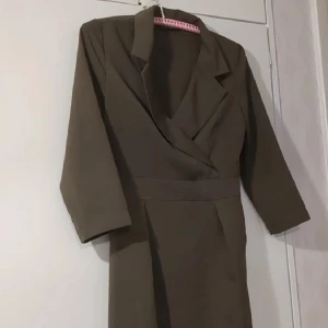 Olivgrön klänning med omlott-design - Vintage 50-tals klänning från Sellpy! Utmärkt skick men passar tyvärr inte mig, kan inte dra upp dragkedjan på sidan vid midjan helt. Passform: XS/S. Jag bär vanligtvis M.