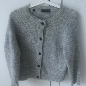 Grå kofta från Selected Femme - Mysig grå kofta från Selected Femme med knappar framtill. Perfekt för kyliga dagar med sin stickade design och långa ärmar. En stilren och bekväm tröja för alla tillfällen.