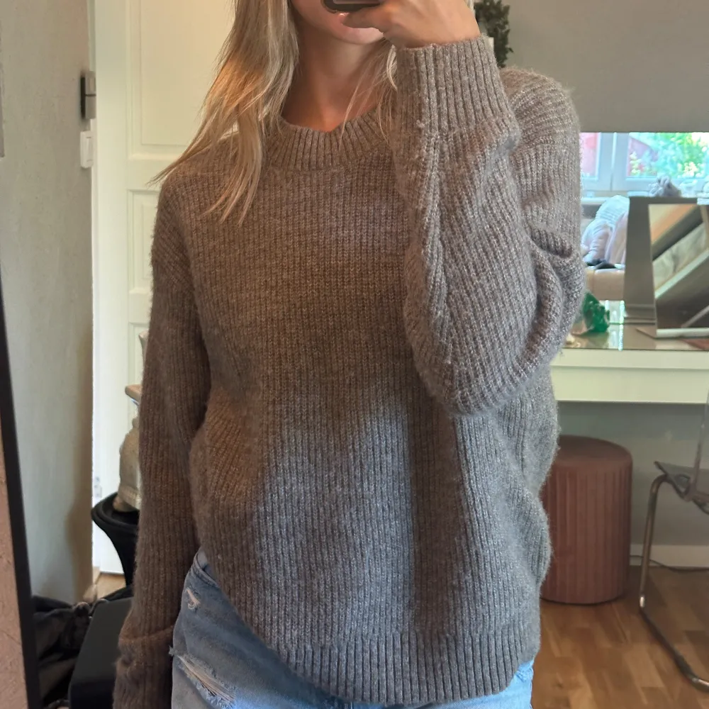 Säljer en supermysig beige stickad tröja från H&M. Den är perfekt för höst och vinter med sin varma och sköna känsla. Tröjan har en normal passform och långa ärmar, vilket gör den idealisk för kyliga dagar. Den är i nyskick och passar perfekt till ett par jeans eller leggings. Perfekt för både vardag och mysiga hemmakvällar!. Tröjor & Koftor.