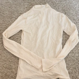 Vit polotröja från H&M - Säljer en vit polotröja från H&M i storlek XS. Tröjan är långärmad och gjord av ett mjukt och bekvämt material. Perfekt för höst- och vinterdagar när du vill hålla dig varm och snygg. Tröjan är i nyskick och har aldrig använts. Passar bra till både jeans och kjol. Köp den nu och uppgradera din garderob! 💫