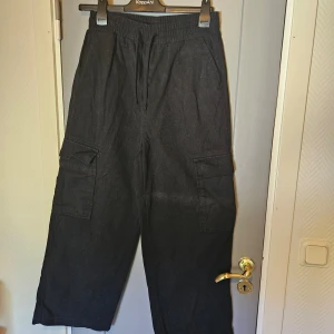 Svarta cargopants från Collusion - Säljer ett par svarta cargopants från Collusion. loose passform. De har flera fickor på sidorna och en snörning i midjan. bra skick, knappt använda, säljer då de inte är min stil. hittar inte storleken men borde vara S