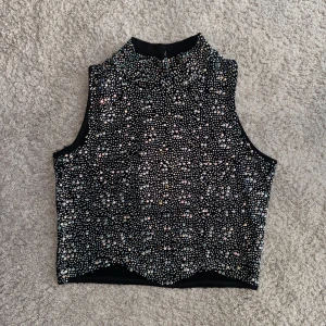 Croptop med strasstenar  - Turtleneck Croptop med strasstenar. Perfekt topp till kostymbyxor!  Använd en gång, Stl XS från Chiquelle 