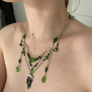 Unikt halsband med gröna och svarta pärlor - Säljer ett supercoolt halsband med flera kedjor och hängande gröna och svarta pärlor. Halsbandet har en mix av gröna droppformade pärlor och små svarta pärlor, vilket ger det en riktigt unik och bohemisk look. Perfekt för att piffa upp vilken outfit som helst! 💚🖤