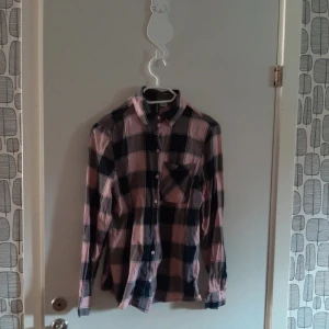 Rutig skjorta - Rosa och svart rutig skjorta. Använd många gånger men i ett hyfsat bra skick.  100% bomull,  medföljer två extraknappar ifall någon skulle lossna. 