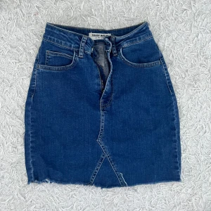 Blå jeanskjol från Tally Weijl - Säljer en snygg blå jeanskjol från Tally Weijl. Kjolen har en tight passform och är kort i modellen. Den har en dragkedja fram och en cool asymmetrisk detalj längst ner. Perfekt för både vardag och fest! 💙