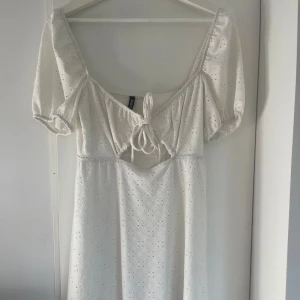 Vit klänning med knytning - Säljer en superfin vit klänning med knytning framtill från HM. Den har korta ärmar och kort i modellen.  Endast använd en gång, i storlek S
