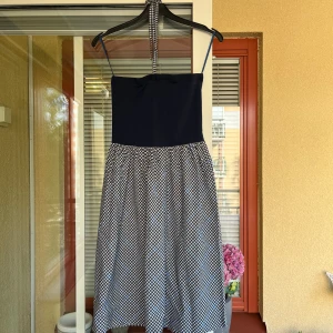 Söt sommarklänning från MEXX - Supersöt klänning med blått liv och mönstrad kjol i mörkblått, blått och vitt rutmönster. Endast använd handfull ggr. Avtagbart knytband runt halsen. Blått liv har stretch. Längd ca 77 cm.