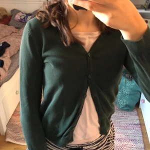 Mörkgrön kofta för barn - Säljer en mörkgrön kofta för barn i storlek 8-9 år, men passar ganska bra för 164. Koftan är perfekt för höst och vinter, och den har långa ärmar och knappar framtill. Den är i bra skick och väldigt mysig att ha på sig. Perfekt för att hålla sig