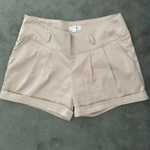 Lågmidjade shorts - Fina beiga shorts i blankt material! Aldrig använda, då det inte är min storlek. Lågmidjade, storlek M 🩶