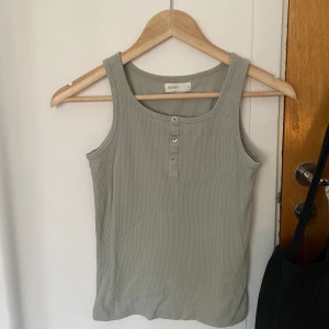 Ribbat linne - Gulligt ribbat linne med knappar framtill från Lager 157. Ljus dämpad turkos pastellfärg, typ ljusgrön/grå. Storlek XS/S. Köpt förra sommaren, inga defekter men passar mig ej längre. Tryck gärna på ”köp nu” knappen! Skickas inom 24h efter man köpt.✨