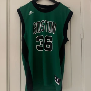 Grön basketlinne från Adidas - Säljer en grön basketlinne från Adidas med texten 'BOSTON' och nummer 36 på framsidan. På baksidan står det 'SMART' med samma nummer. Linnet är ärmlöst och har svarta detaljer längs sidorna och runt ärmhålen. Perfekt för basketfans eller som en cool vardagströja! 🏀