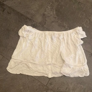 Vit offshoulder blus - Säljer en söt vit offshoulder blus i bomull. Den har knappar framtill och en fin spetsdetalj runt midjan. Perfekt för sommardagar eller en avslappnad vårlook. Blusen är i bra skick och passar till både jeans och kjol.
