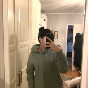 Grön hoodie med tryck - Säljer en grön hoodie med texten 'Good Things Are Coming' i vitt på ryggen. Den är supermjuk och perfekt för mysiga dagar. Det finns en liten fläck på baksidan, men annars i bra skick. Perfekt för höst och vår!