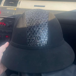 Charles Owen SP8 - Säljer en elegant svart hjälm från Charles Owen, modell SP8 Plus. Hjälmen har en glittrig detalj på ovansidan och är handgjord i Storbritannien. Perfekt för ridning med stil och säkerhet. Den är i nytt skick, aldrig använd och bara provad.