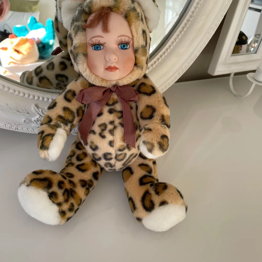 Söt vintage docka från år 1988 helt ny klädd i en leopardmönstrad dräkt .armar ,ben är rörliga.. Perfekt som dekoration eller leksak för samlare. Dockan har ansikte är i porslin med ögonfransar, .tvätta i tvättmaskinen 30 grader . Längd:33cm och bred 18cm. Asusteet.