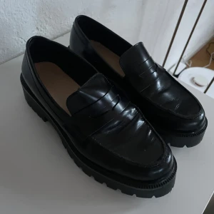Svarta loafers i skinn - Snygga svarta loafers i skinn med en klassisk design. Perfekta för både vardag och fest. De har en robust sula som ger bra grepp och komfort hela dagen. Passar till både jeans och kostymbyxor. Ett måste i garderoben för en stilren look! Kvitto finns 