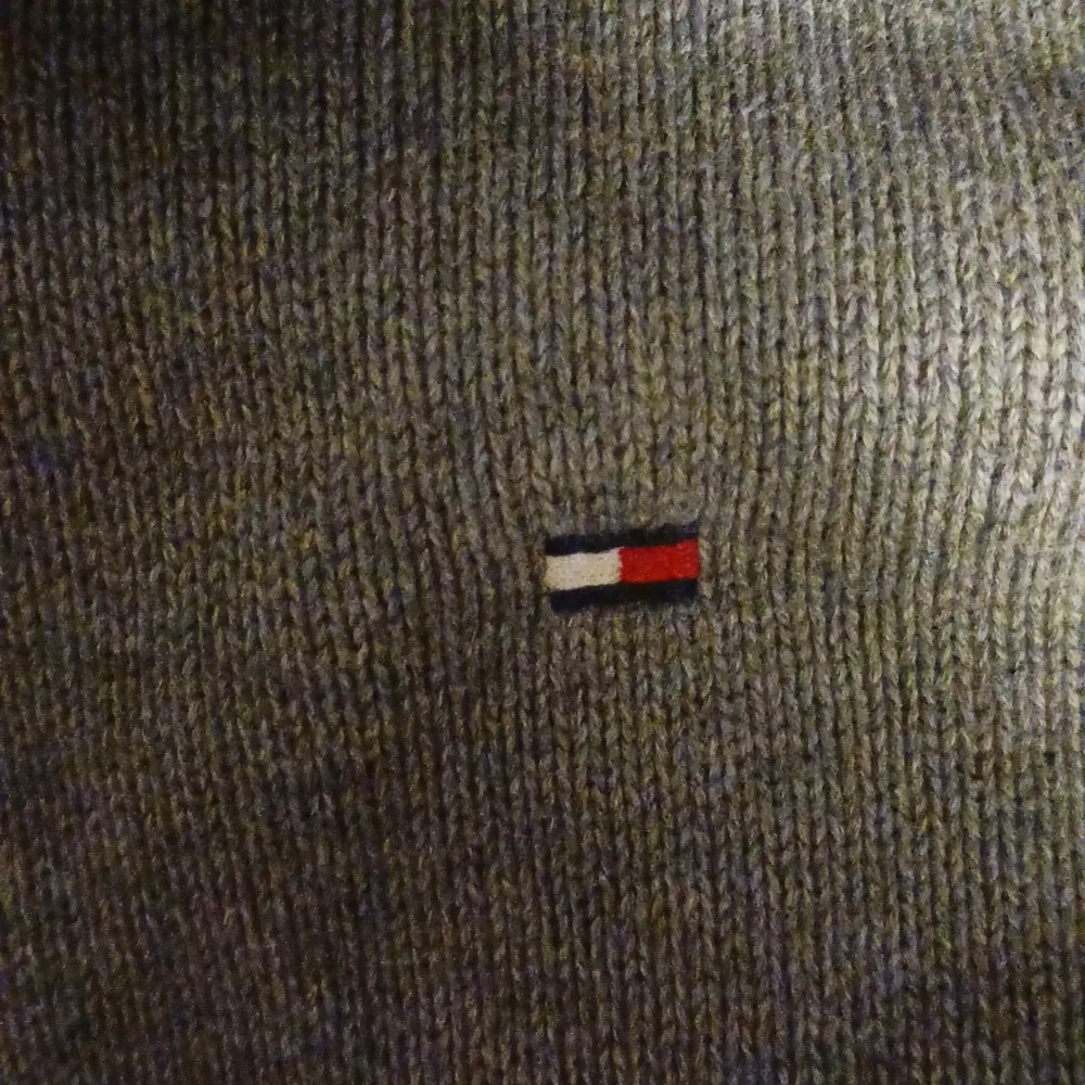 Säljer en stilren grå stickad tröja från Tommy Hilfiger i storlek M. Tröjan har en liten broderad logga på bröstet och är perfekt för både höst och vinter. Den är i mycket bra skick och passar till både vardag och fest. Skön och varm, perfekt för kyliga dagar!. Tröjor & Koftor.