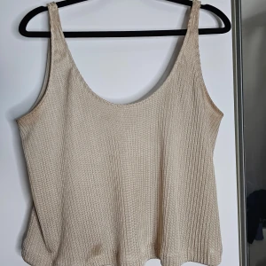 Guldig topp från stradivarius - Stilren guldig ribbad linnetopp från stradivarius i storlek M, men vill hävda att den passar ända upp till XL. Perfekt för sommardagar med sin lätta och luftiga design. Toppen har en enkel och stilren look med breda axelband och en rund halsringning. Inga defekter, slitstarkt material. 