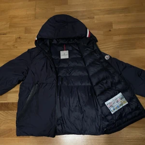 Moncler Melampyre Down Puffer Jacket - Köpt på Vestiare men säljes då den inte passar ägaren. Nypris är ca 14 000kr och just denna modell är extremt efterfrågad därmed svår att få tag i eftersom den är slutsåld nästan överallt. Jackan är äkta och det går enkelt att bevisa genom NFC taggen eller QR koden på insidan som tar dig till monclers hemsida där dem bekräftar att just din jacka med ditt serie nummer är äkta. Hör gärna av dig om du har frågor!