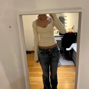 Vit ribbad topp - Säljer en stilren vit ribbad topp med långa ärmar och en v-ringad design. Perfekt för en trendig look.