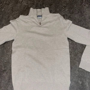 Beige tröja med dragkedja från Jack & Jones - Säljer en stilren beige tröja från Jack & Jones i storlek XS. Tröjan har en praktisk dragkedja vid halsen och är tillverkad i ett mjukt material. Perfekt för en avslappnad look.