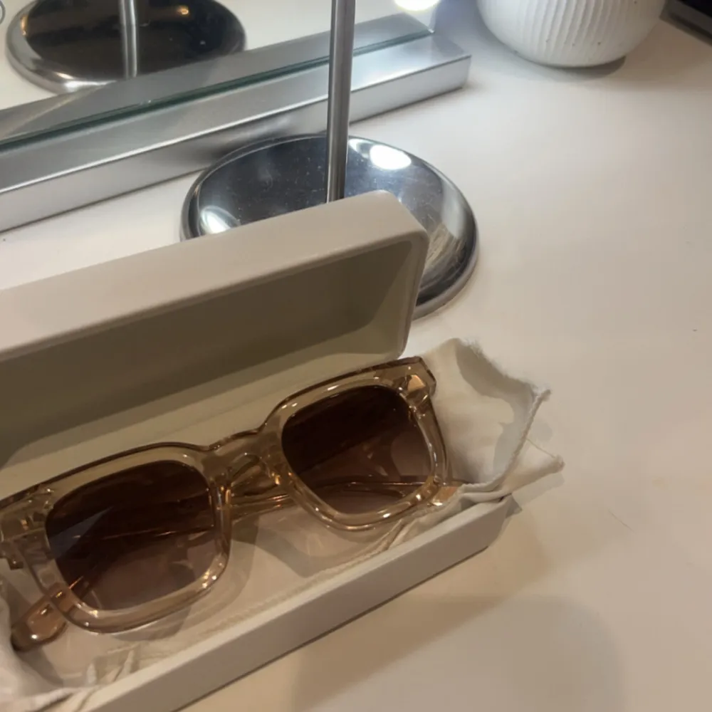 Snygga transparenta solglasögon från Chimi med fyrkantig form och bruna tonade linser. Perfekta för en stilren look. Kommer med ett matchande fodral.. Asusteet.