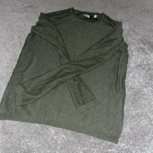 Olivgrön tröja från Jack & Jones - Säljer en stilren olivgrön tröja från Jack & Jones. Tröjan har en klassisk rund hals och långa ärmar, perfekt för en avslappnad look. Tillverkad i ett mjukt material som känns skönt mot huden.