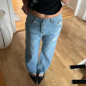 Ljusblå jeans med slitningar - Säljer ett par ljusblå jeans i mycket bra skick! De har en loose passform och är högmidjade, vilket ger en avslappnad och trendig look! Jenssen har snygga slitningar fram, och Cilla fickor. Storlek: M (jag är 172)
