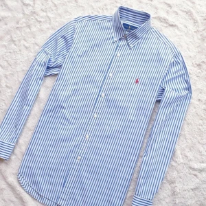 Ralph Lauren Skjorta - Hej! Säljer en blåvit randig skjorta i storlek M, med button-down-krage och röd broderad logga på bröstet. Utmärkt skick utan tecken på användning. Perfekt för både vardag och formella tillfällen.  Hör av dig vid eventuella frågor!