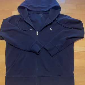 Ralph Lauren Zip Hoodie - Hej, säljer nu denna Navy Blue zip hoodien från Ralph Lauren. Fortfarande i väldigt bra skick då den blev bra omhändertagen och tvättad. Luvan är det enda som krympt väldigt lite men värt att notera men annars helt i nyskick!                                         Hör gärna av er vid frågor!😃