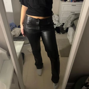 Svarta skinnbyxor från Bik Bok - Snygga svarta skinnbyxor från Bik Bok i storlek 40. Byxorna har en klassisk design med knappar och dragkedja framtill. Perfekta för en stilren look.