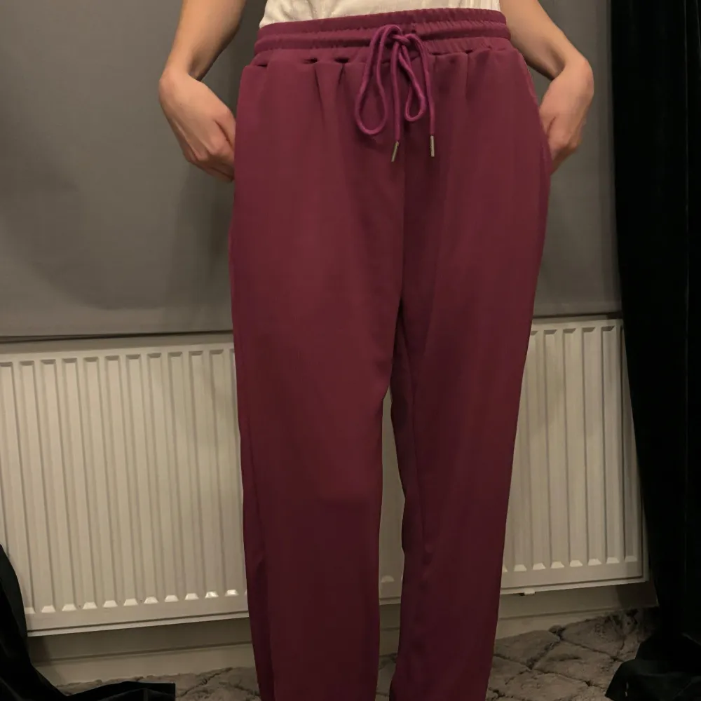 Snygga lila mjukisbyxor med elastisk midja och snörning. Byxorna har en avslappnad passform och är perfekta för en bekväm stil. De är gjorda i ett mjukt material som känns skönt mot huden.. Farkut & Housut.