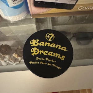 Banana Dreams Loose Powder - Banana Dreams Loose Powder från W7 är ett löspuder i en ljusgul nyans. Perfekt för att sätta sminket och ge en matt finish. Kommer i en rund burk med svart lock och gul text.