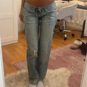 Blå jeans med slitningar, lågmidjade - Snygga blå jeans med slitningar på ena benet. De har en klassisk femficksdesign och en knappgylf. Perfekta för en avslappnad stil. Midjemåttet är 36 cm och inner ens längden 76 cm