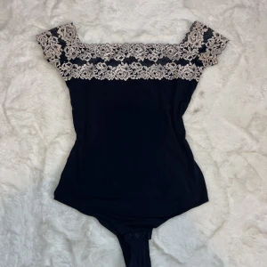 Marinblå offshoulder topp med spetsdetaljer från Intimissimi - Elegant marinblå offshoulder topp från Intimissimi med vackra spetsdetaljer i beige runt halsen och ärmarna. Perfekt för en stilren look. Köptes av en tjej som skrev att den var i storlek S men såg att det var M så jag har inte kunnat använda den tyvärr! ☺️