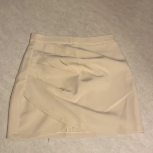 Beige kjol från Amisu - Snygg beige kortkjol från Amisu med en stilren design. Kjolen har en dragkedja baktill för enkel på- och avtagning. Perfekt för att skapa en chic look.