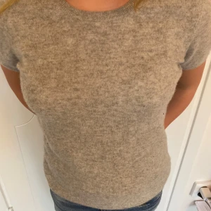 Grå kashmirtröja - Säljer en mjuk och stilren grå tröja i 100% kashmir. Tröjan har korta ärmar och en rund halsringning, perfekt för en elegant och bekväm look. Passar bra till både jeans och kjol.