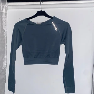 Mörkgrå croppad träningstopp från ICIW - Snygg mörkgrå croppad träningstopp från ICIW med långa ärmar. Perfekt för gymmet eller löprundan. Toppen har en stilren design med logotypen tryckt på framsidan.