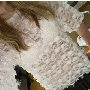 Vit spetsblus - Säljer en elegant vit spetsblus med korta ärmar och ett unikt mönster. Perfekt för att ge en stilren touch till din outfit. Blusen har en luftig och bekväm passform.