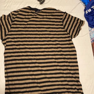 Randig t-shirt från Redwood - Säljer en randig t-shirt från Redwood i svart och beige. Den har korta ärmar och är perfekt för en avslappnad stil. Storlek XXL.